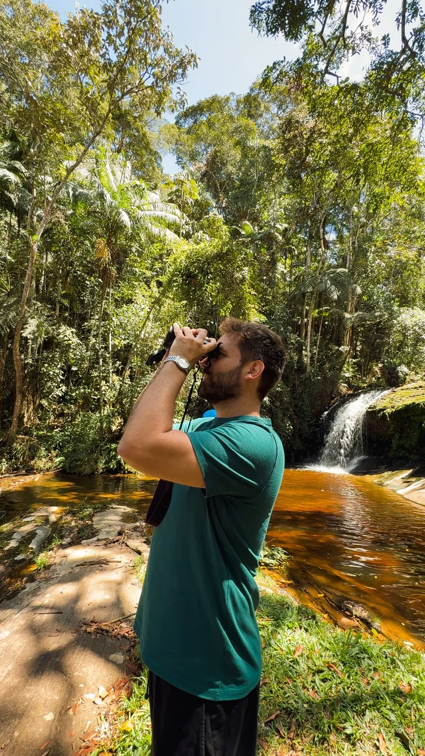 Rena fotografando em meio à natureza e uma cachoeira